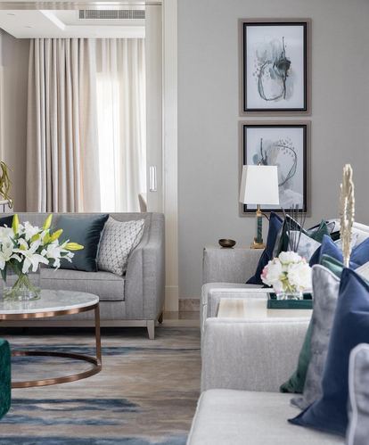 Grey living room with marble coffee table, navy pillows, and framed abstract art above a console