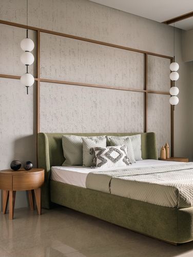 Olive green upholstered bed against textured wall with wood grid frame and sphere pendant lights
