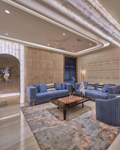 Living room with blue velvet sofas, marble coffee table, patterned rug, and illuminated stone ceiling panels