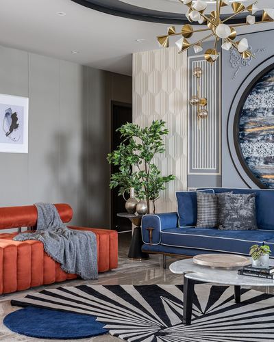 Living room with rust velvet sofa, navy sofa, round artwork, and sculptural gold chandelier