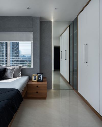 Bedroom with grey stone wall, wardrobe corridor with backlit mirror strip, city view window