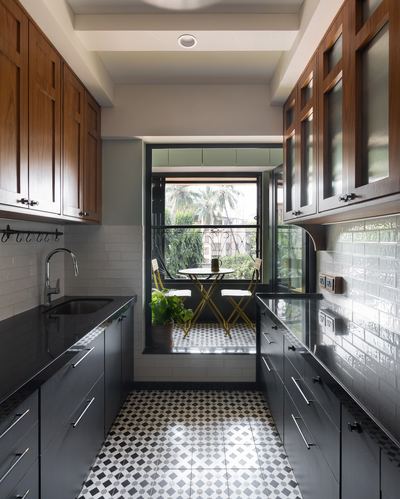 Galley kitchen with wood cabinets and patterned tile floor leading to a glazed balcony seating nook
