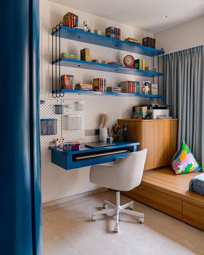 Blue floating desk and shelves in a child's study nook with wooden storage and daybed