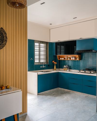 Teal L-shaped modular kitchen with ribbed backsplash tile, white countertop, and fluted wood partition wall