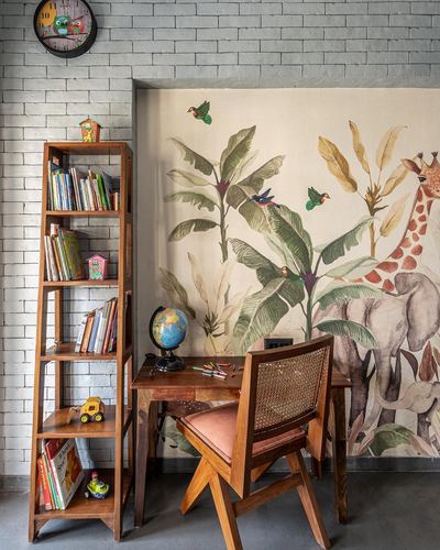 Child's study nook with ladder bookshelf, wooden desk, cane chair, and jungle-themed mural