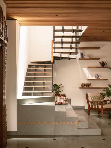 Staircase with wood-slat ceiling, stone steps with inlay detail, and floating shelves with brass objects