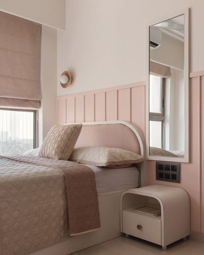 Pink-paneled bedroom with curved upholstered headboard, rounded nightstand, and tall mirror beside window