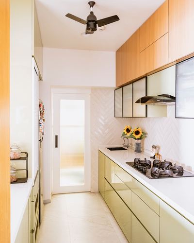 Galley kitchen with olive cabinetry, wood overhead units, herringbone tile backsplash and glass door at end
