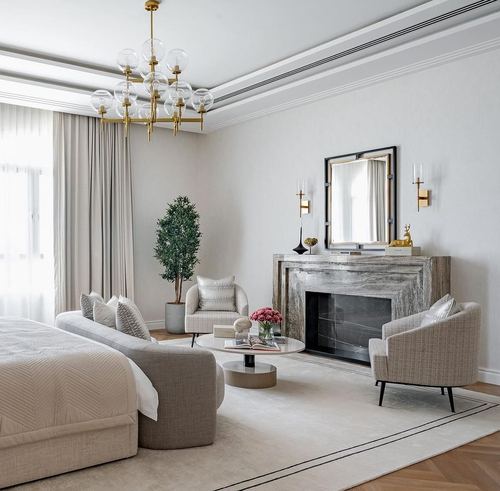 Neutral master suite with sofa bed, marble fireplace, arched mirror and gold chandelier