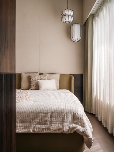 Beige bedroom with olive leather headboard, fluted wood wall, and layered lantern pendants by sheer curtain