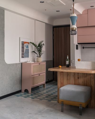 Pastel pink cabinet and cane doors beside a wooden kitchen island with pendant light