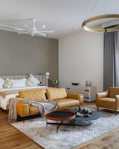 Bedroom with mustard leather sofa, bed, and round brass pendant light over sitting area