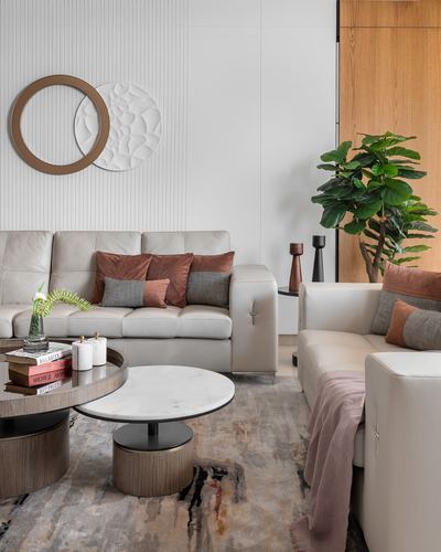 Living room with cream leather sofas, marble-top coffee table, fluted wall and circular mirrors