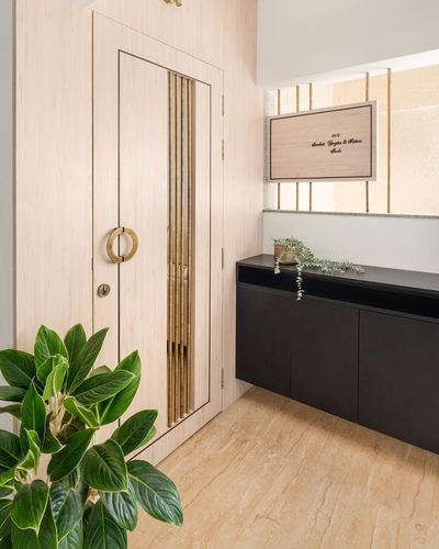 Entryway with fluted brass-inlaid wooden door, black floating console, and marble floor