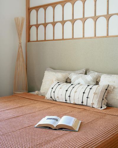 Bedroom with arched wood headboard, terracotta waffle bedspread, and layered textured pillows