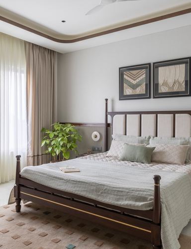 Bedroom with dark wood four-poster bed, upholstered headboard, framed art, and sheer curtains