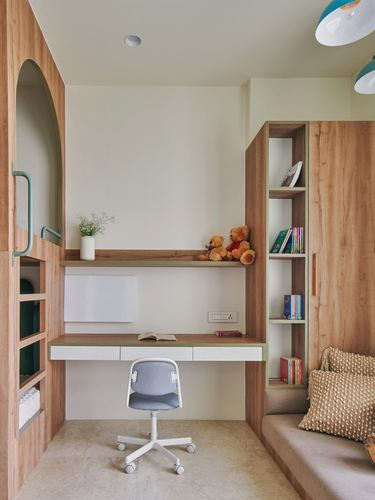 Built-in wooden desk with open bookshelf and arched niche in a children's study nook