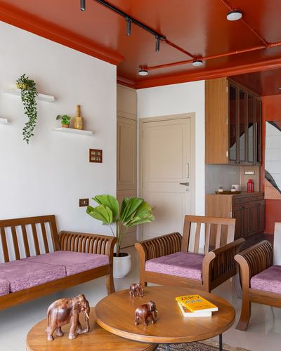 Living room with orange lacquered ceiling, wooden sofa set with purple cushions, round coffee table