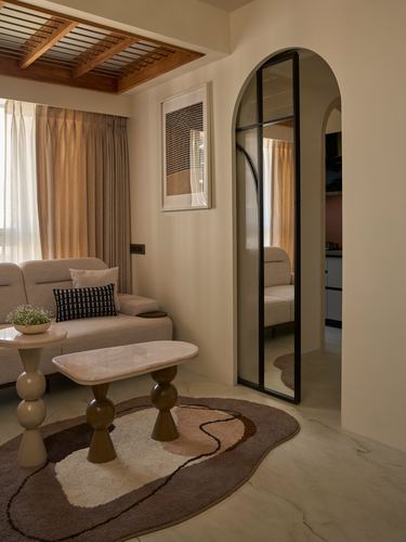 Living room with arched glass door, wooden slatted ceiling, marble coffee table and rounded stool bases on a patterned rug