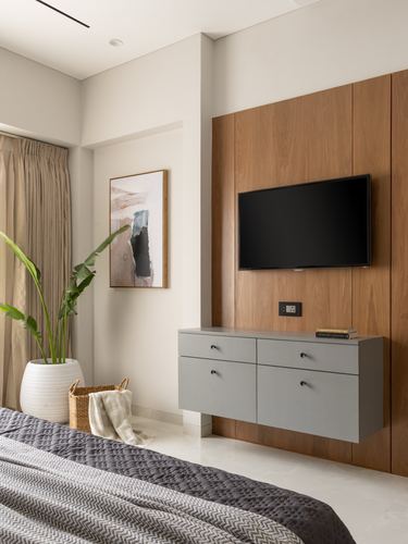 Bedroom with wood-panelled wall, mounted TV, floating grey console and framed art beside curtain