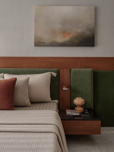 Bedroom corner with green velvet headboard, wood panelling, floating nightstand and framed art