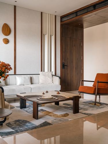 Living room with white sofa, orange armchair, carved wooden coffee table and patchwork rug