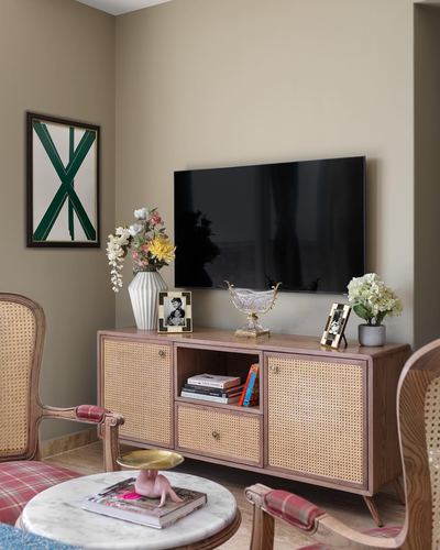 Living room corner with cane console under wall-mounted TV, cane armchairs, marble coffee table