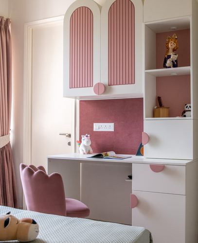 Child's study nook with pink arched fluted cabinets and scalloped velvet chair