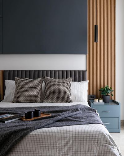 Bedroom with dark accent wall, fluted wood panel, channel-tufted headboard and blue bedside table