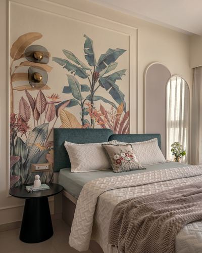 Bedroom with teal velvet headboard, tropical leaf mural, and arched mirror by window