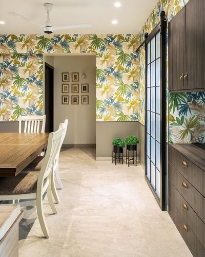 Dining area with tropical wallpaper, wooden table, and dark sliding door leading to cabinetry