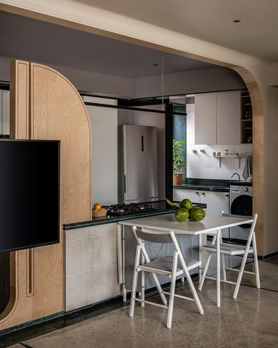 Kitchen nook with curved wood archway, green stone counter, dining table with coconuts and folding chairs
