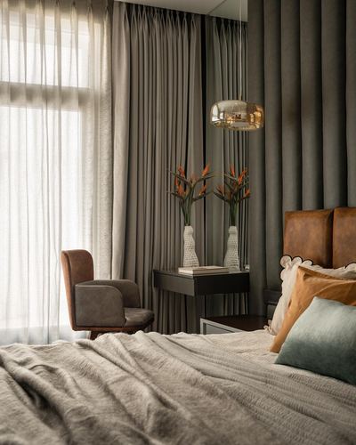 Bedroom corner with leather headboard, brass pendant, and floating console against grey curtains