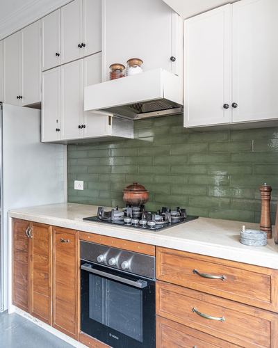 Kitchen corner with green tile backsplash, white upper cabinets, wooden lower cabinets and built-in oven