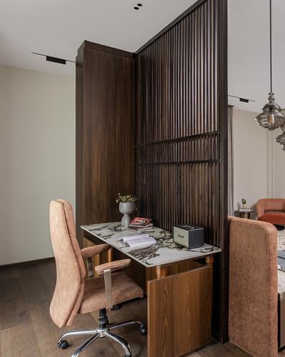 Study nook with marble desk against fluted wood partition, pink leather chair, warm lighting