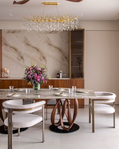 Dining room with marble table on carved wood base under crystal chandelier