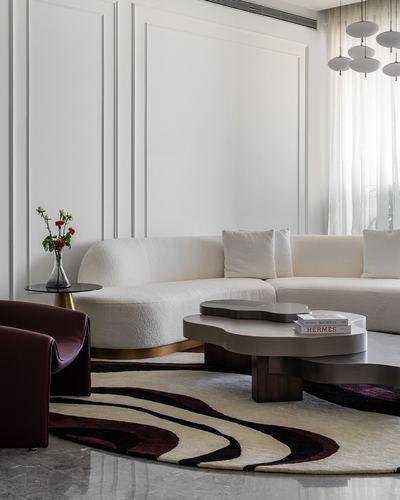 Curved white boucle sofa with organic wooden coffee table on a swirl-patterned rug