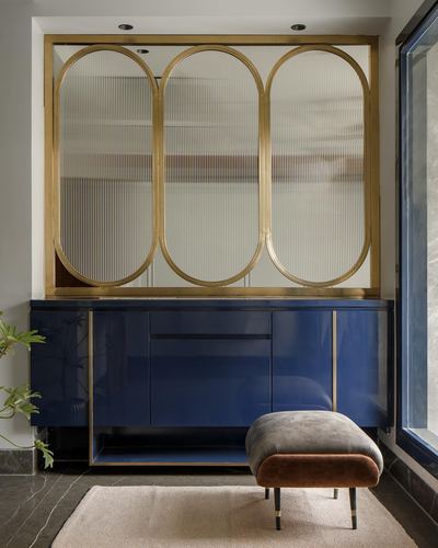 Navy lacquered console below brass-framed fluted glass mirror panels in a foyer