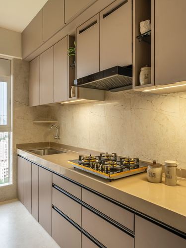 Galley kitchen with taupe cabinetry, stone backsplash, black chimney hood, and gas cooktop on beige counter