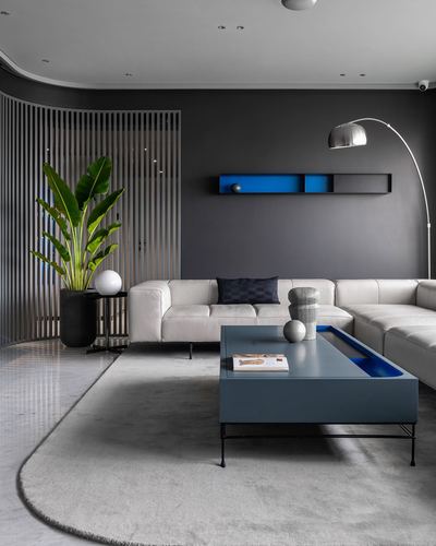 Dark grey living room with white sectional sofa, blue lacquered coffee table and curved wood slat screen