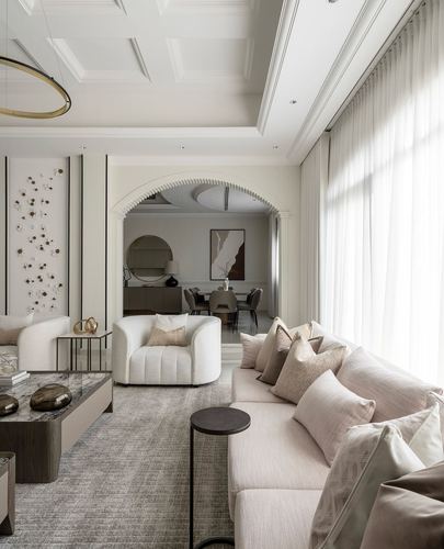 Neutral-toned living room with sectional sofa, arched doorway to dining area, and floor-to-ceiling sheer curtains