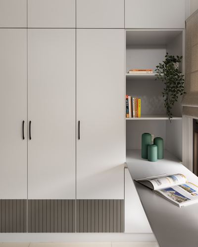 White wardrobe with fluted base panels beside open shelving and a study desk with green vases and a magazine