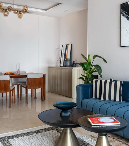 Living room with blue velvet sofa, round black coffee tables, and dining area beyond