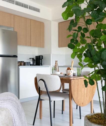 Small kitchen and dining nook with wood cabinetry, round table and large potted plant