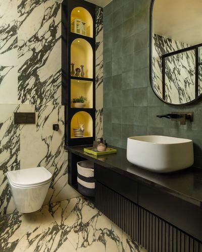 Marble bathroom with backlit arched shelving niche, black vanity, and oval mirror over vessel sink