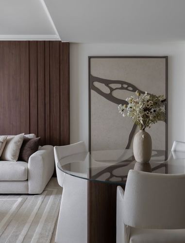 Dining nook with glass table, upholstered chairs, and fluted wood wall beside a living area