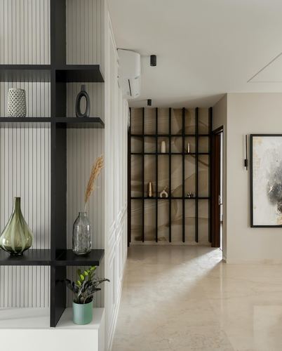 Foyer with black-framed display shelving, glass vases, and a marble-floored passage leading to a lit alcove.