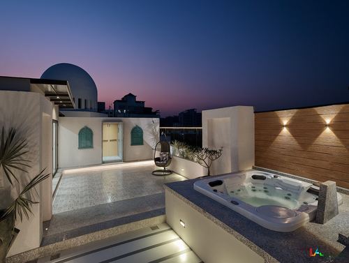 Rooftop terrace at dusk with jacuzzi, hanging chair, arched shutters, and dome structure