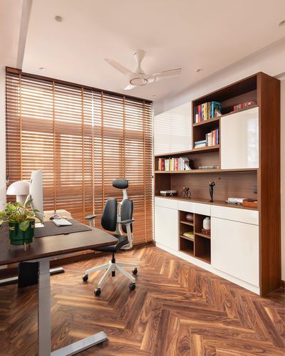 Home office with herringbone wood floor, wooden blinds, and a walnut-and-white shelving unit