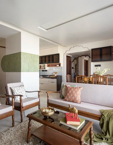 Living room with teak sofa, scalloped archway, and green painted wall niche leading to dining and kitchen